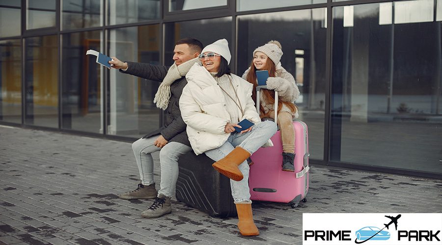 Family of three going on vacation. Man and woman sitting on a luggage and holding passports. Mother, father and daughter wearing warm clothes.