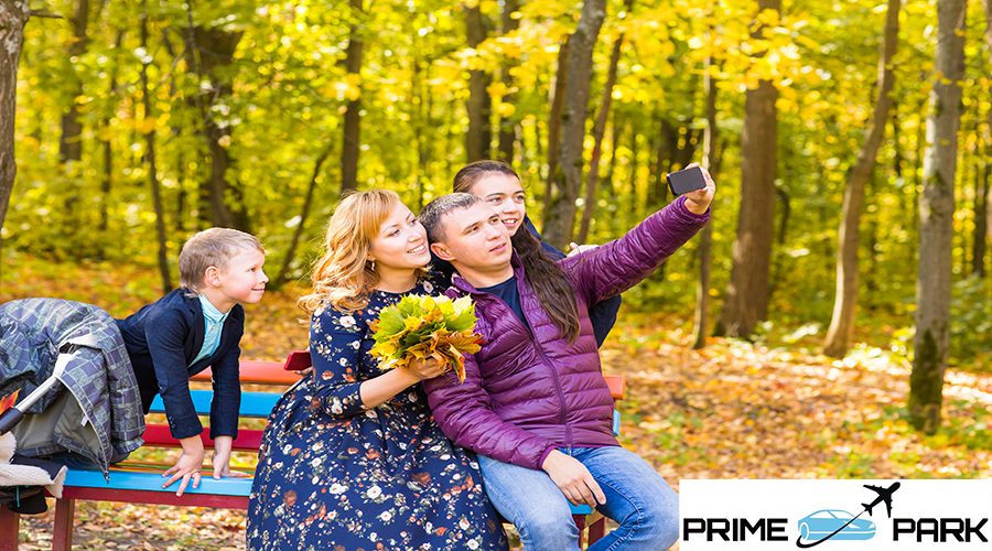 family, childhood, season, technology and people concept - happy family photographing in autumn park.